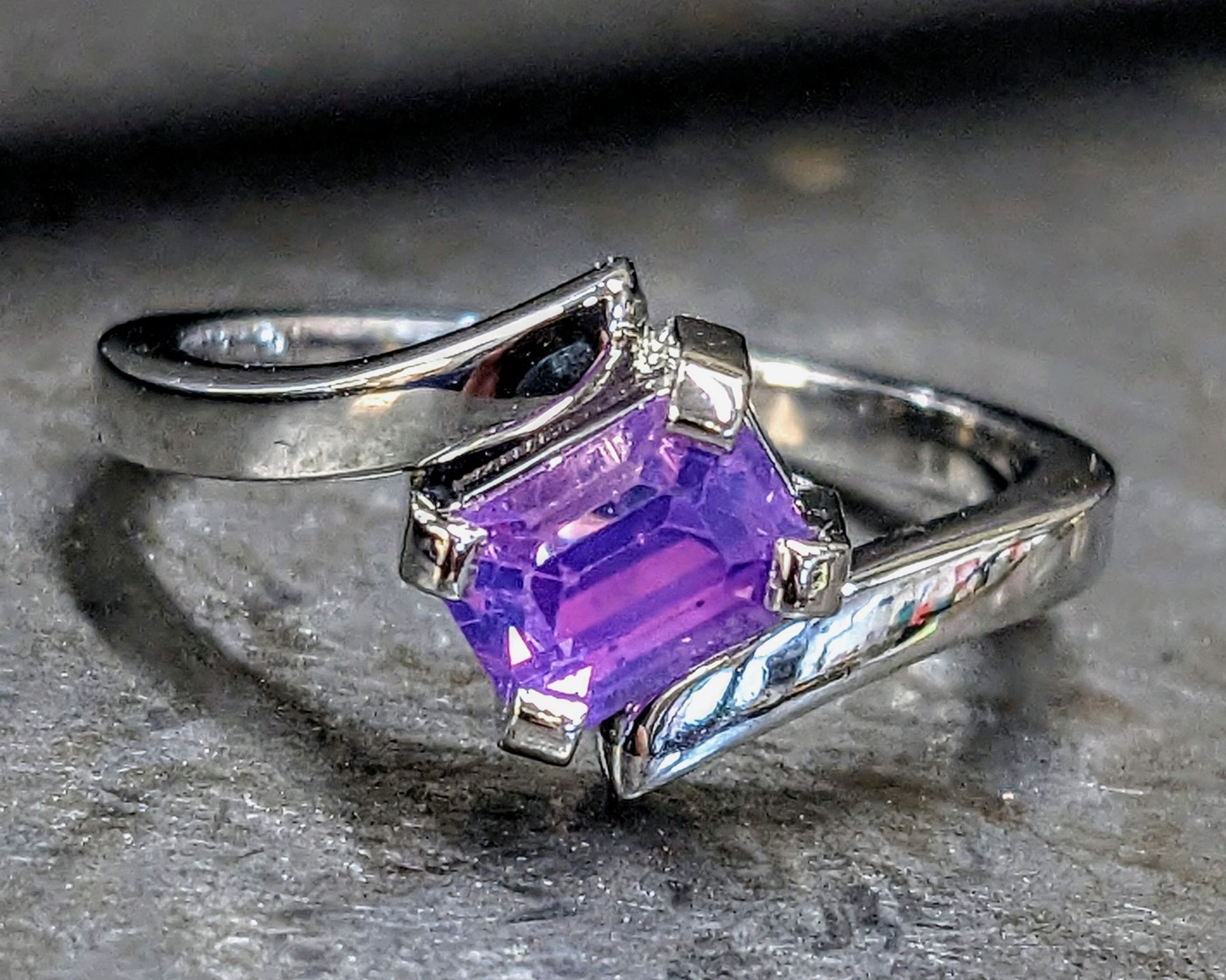 Silver ring with a claw-set, emerald-cut purple gemstone