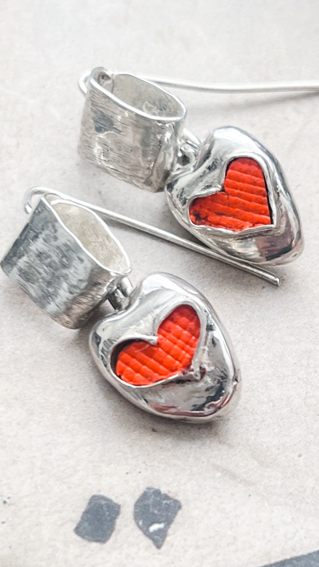 Textured silver heart earrings with red inlay on long hooks