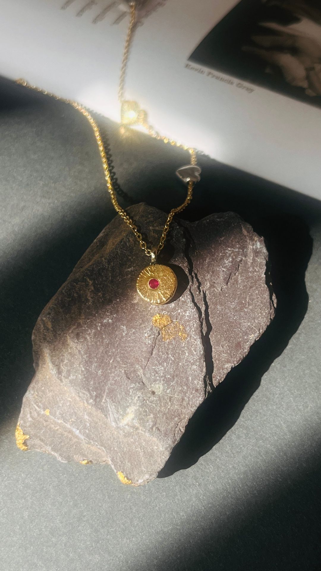 Textured gold disc pendant set with a small red stone