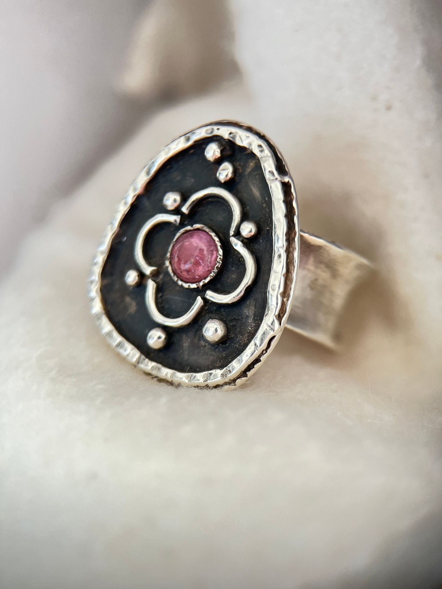 Oxidised silver ring with a quatrefoil motif around a pink stone