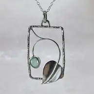 Rectangular silver frame pendant with a leaf and a green stone