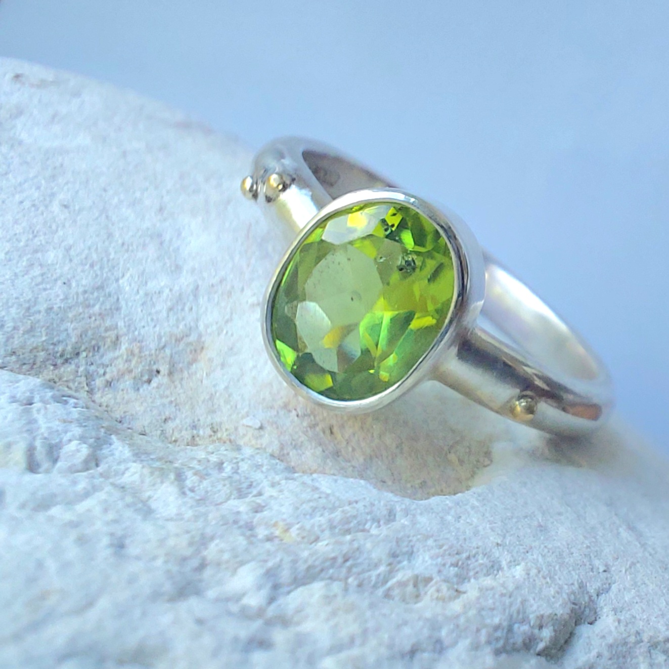 Silver ring set with a faceted green stone and small gold granules