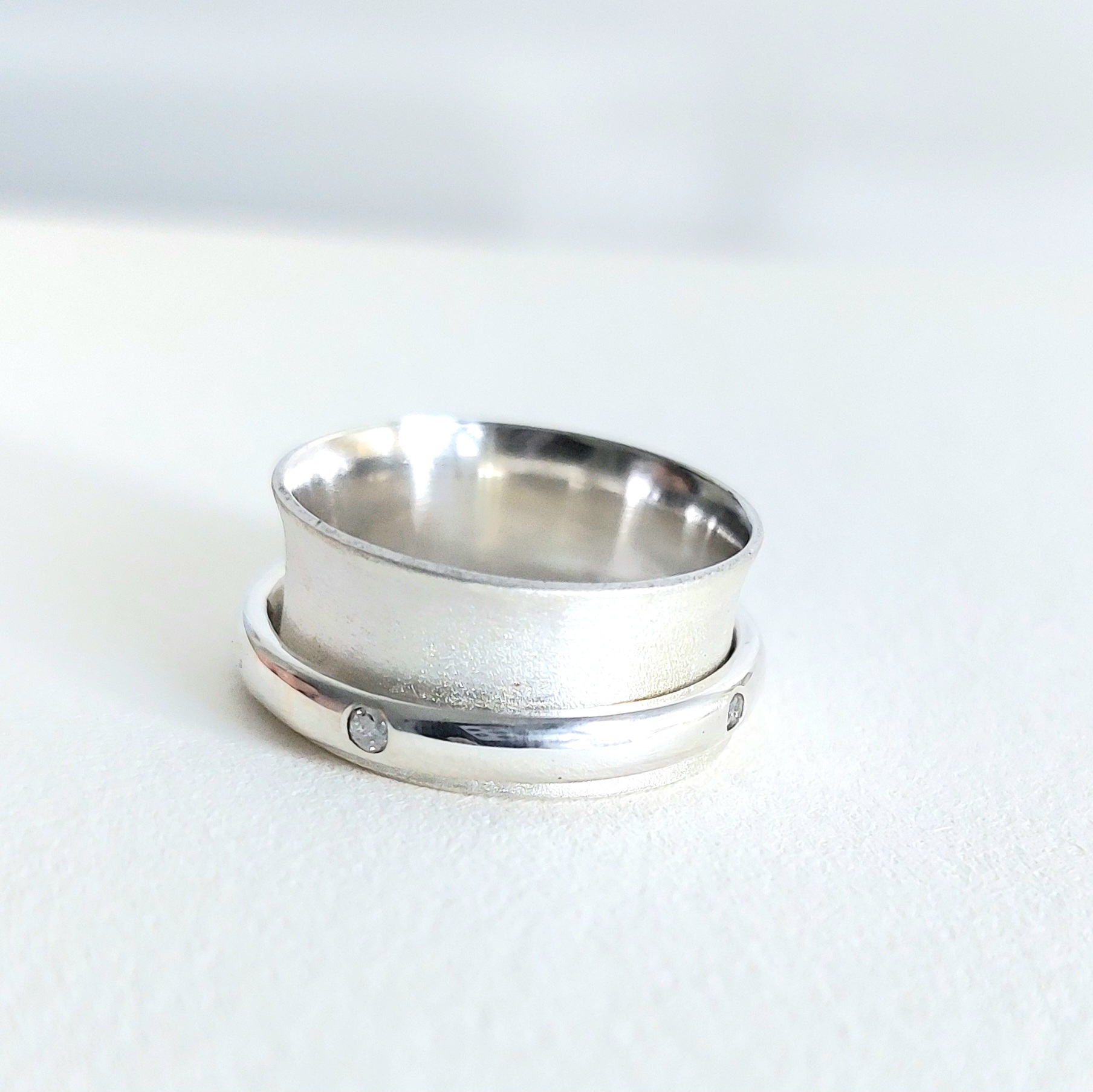 Wide silver ring with a polished band set with small clear stones